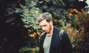 selective focus photography of man standing near tree