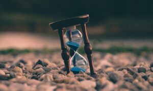 selective focus photo of brown and blue hourglass on stones