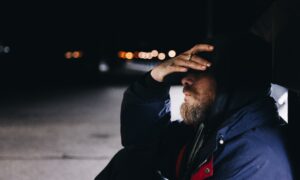 man sitting at the shed beside the street