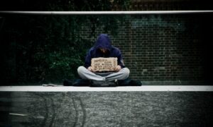 man in blue hoodie reading book on gray concrete road during daytime