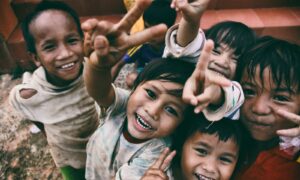 five children smiling while doing peace hand sign