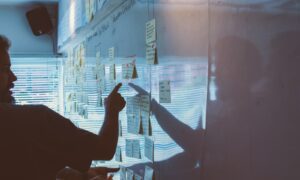 person pointing white paper on wall