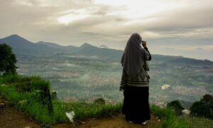 woman in black and white hijab standing on green grass field during daytime