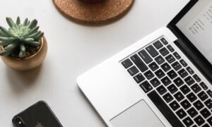 space gray iPhone X beside turned on laptop beside coffee and succulent plant