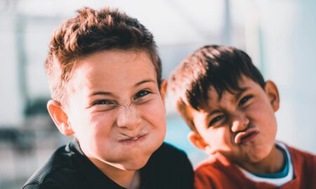 shallow focus photography of two boys doing wacky faces